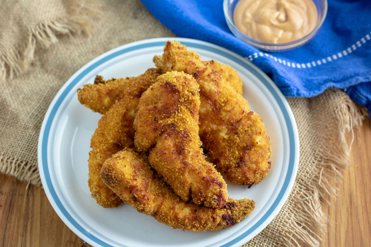 Air fried chicken tenders on white plate with blue highlight.