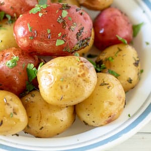 foil packet grilled potatoes in white bowl with blue rim.