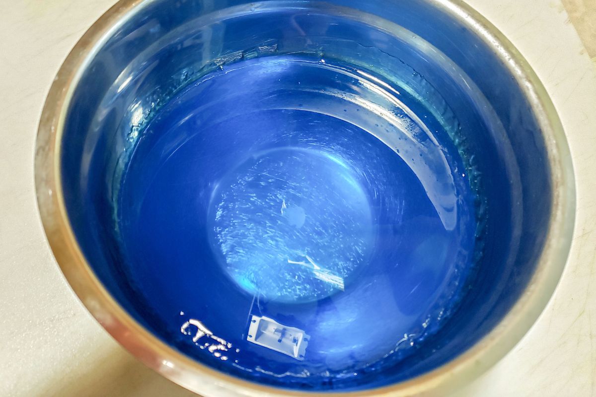 Blue jello mixed in a metal bowl.