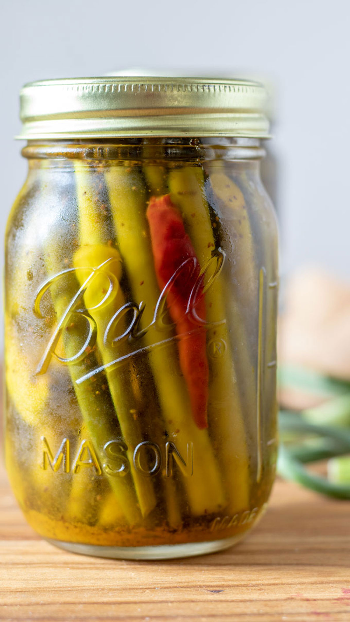 Pint jar cold pack pickled garlic scapes with a red pepper in it.