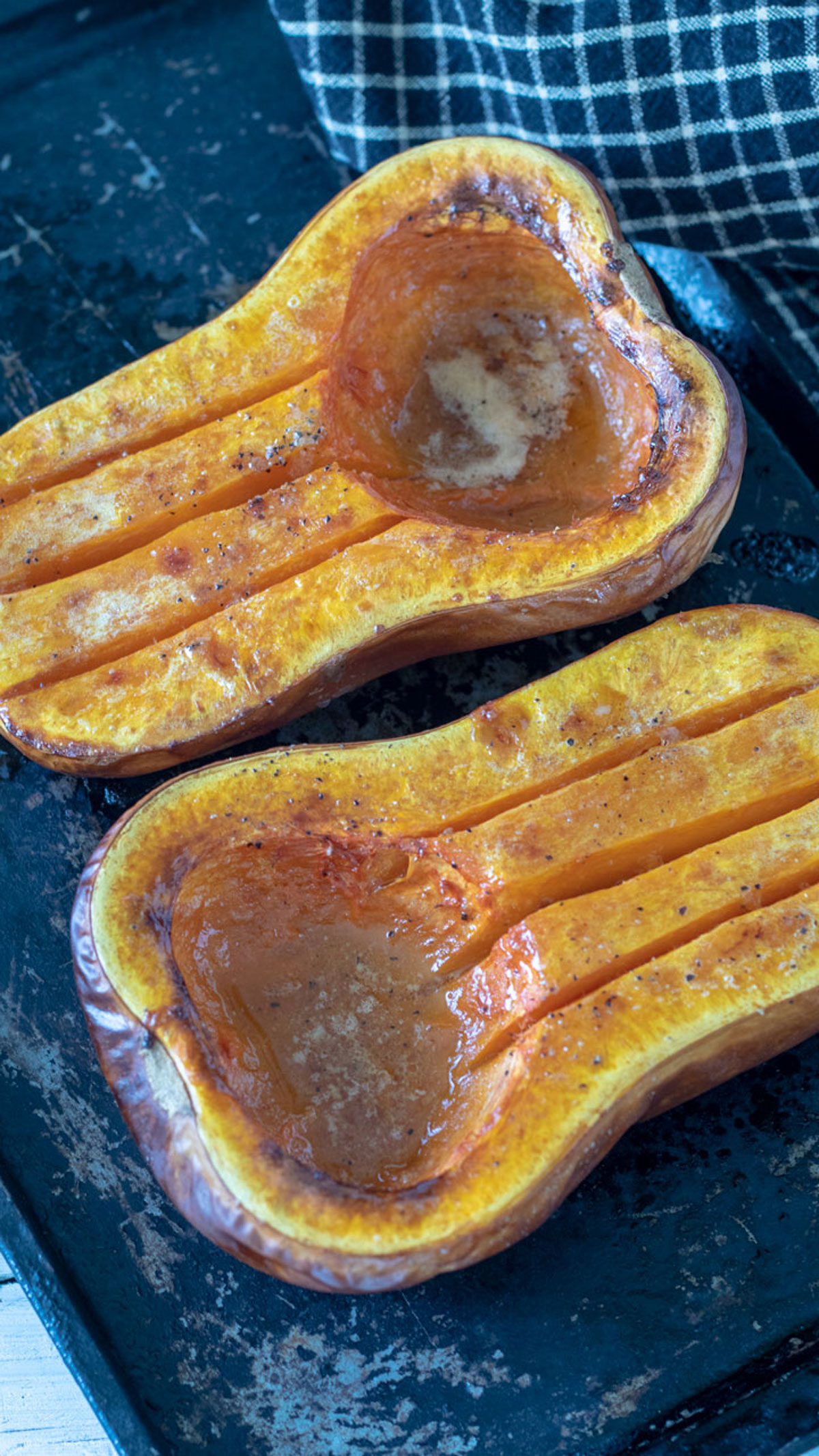 Butternut squash halves on metal baking sheet.