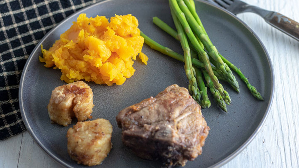 Mashed roasted butternut squash on grey plate.