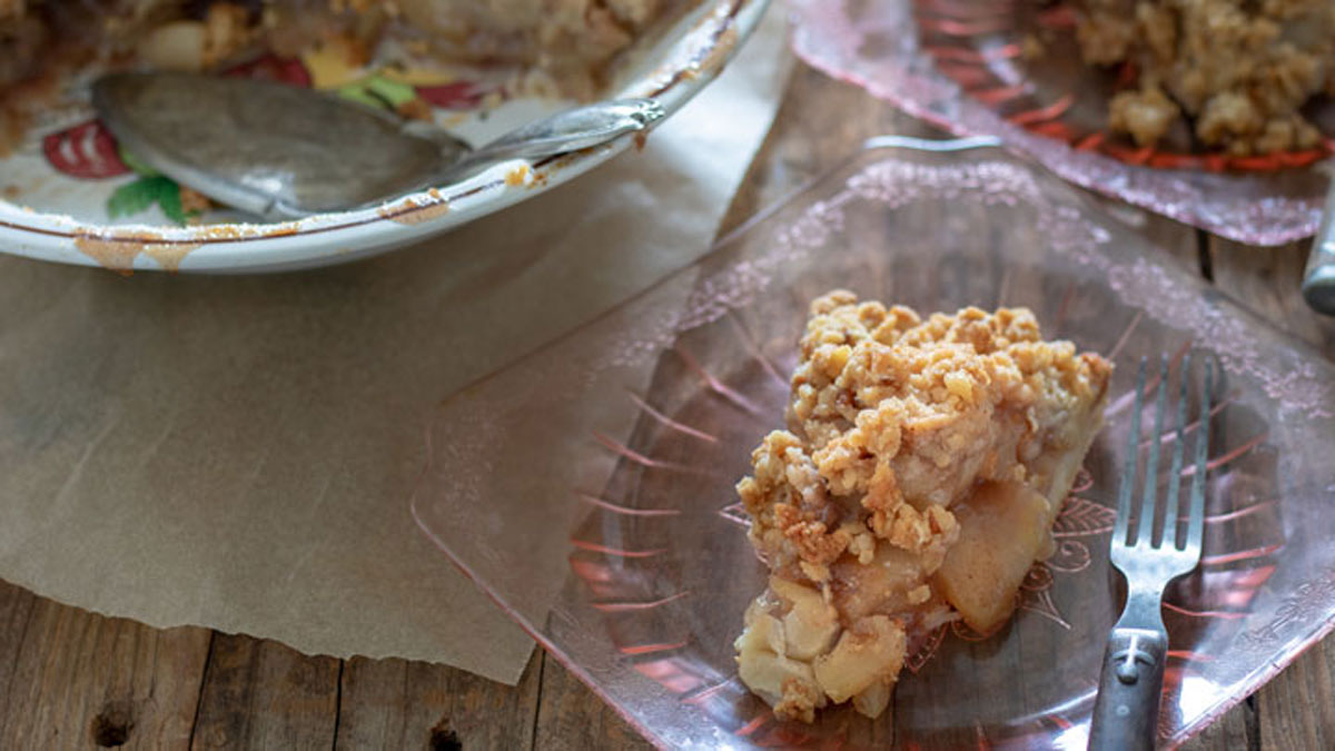 Slice of pie on pink plate with wooden spoon.