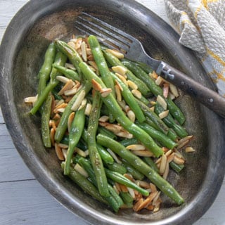 Green beans and almonds, toasted, in silver platter.