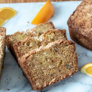 Orange pineapple quick bread sliced on marble board.