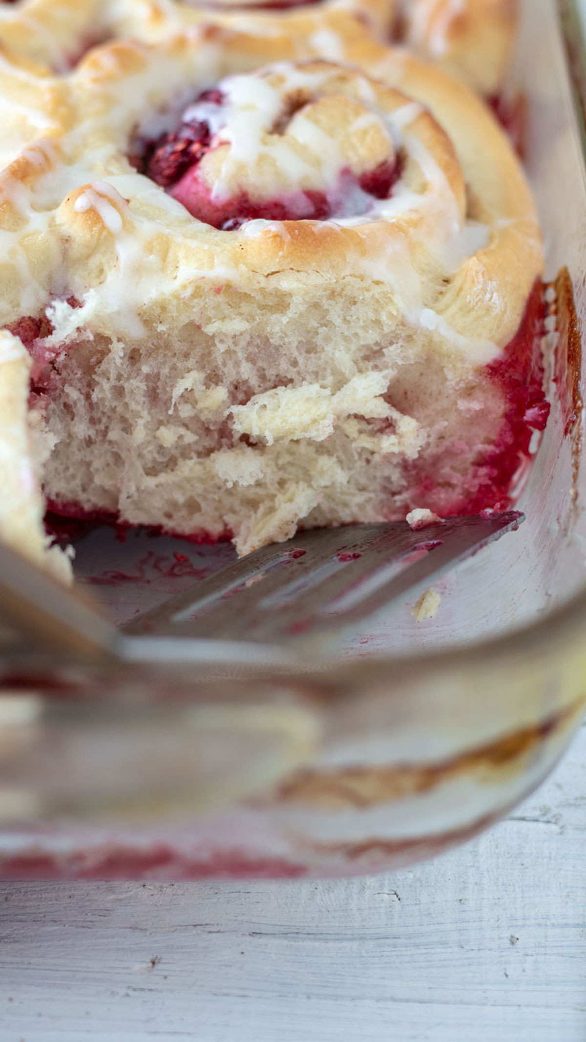 Close up of puffy dough of the raspberry filled cinnamon roll in baking pan.