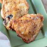 Crispy chicken thighs on green plate.