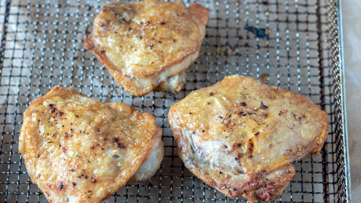 Cooked chicken in air fryer basket.