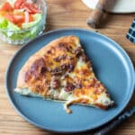 slice of cheeseburger pizza on grey plate.