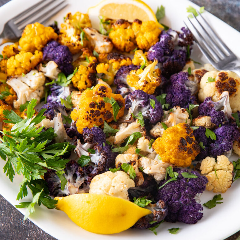 Colorful roasted cauliflower in a white bowl.