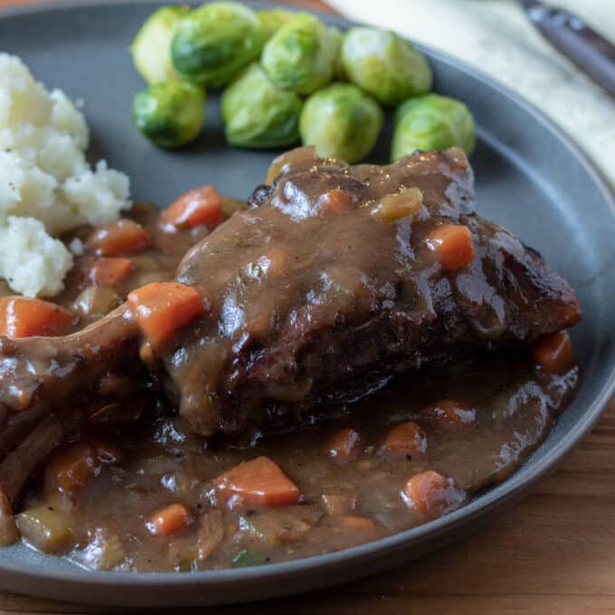 lamb shank with gravy on gray plate