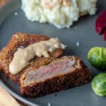chicken fried venison sliced on gray plate with sides