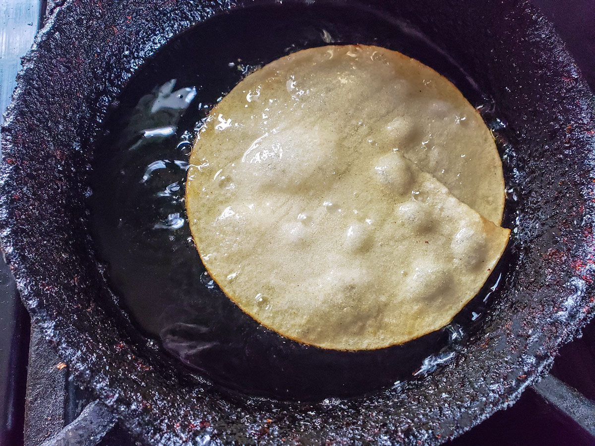 Tortilla bubbling in pan with oil.
