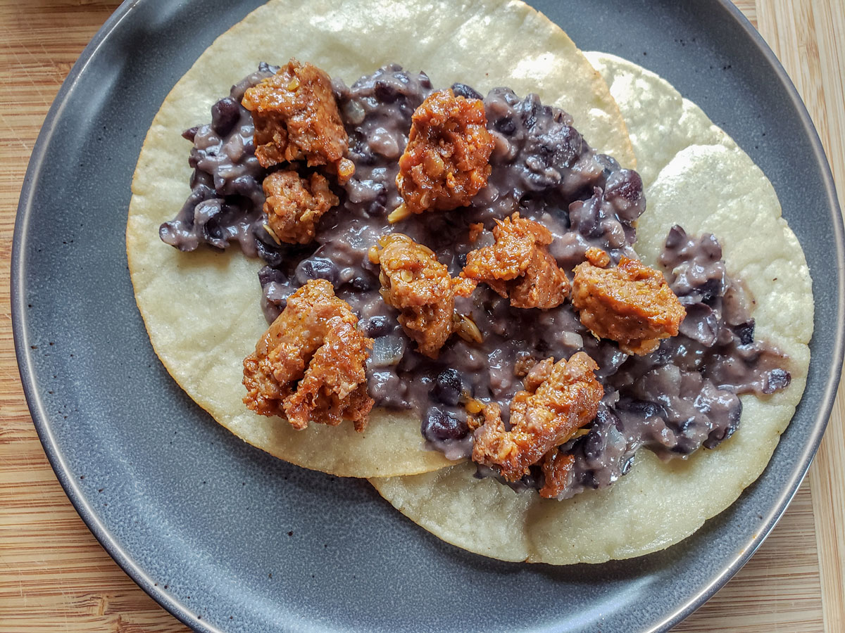 Two tortillas with beans and chorizo spread on top.