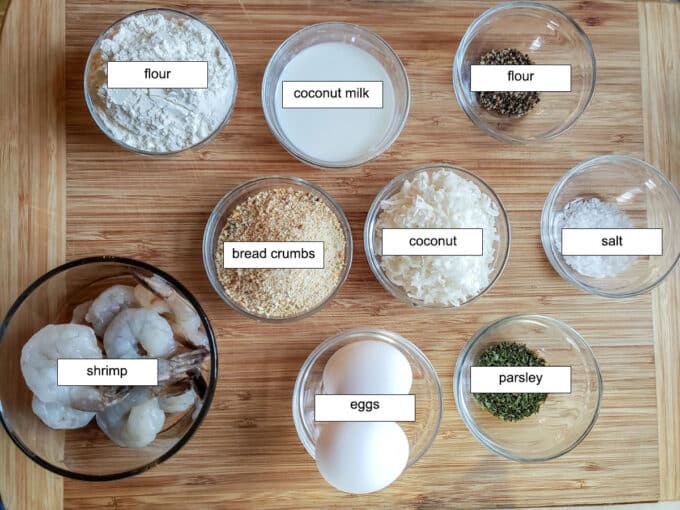 Ingredients for shrimp. Flour, coconut milk, pepper, salt, coconut, bread crumbs, egg, parsley, shrimp.