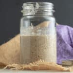 Square image of sourdough starter in glass jar.