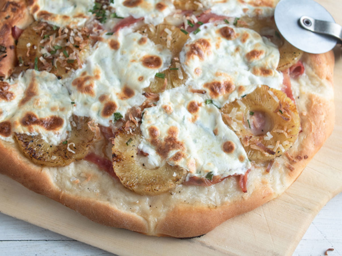 Tasted coconut, pineapple, ham and mozzarella on pizza on wooden peel.