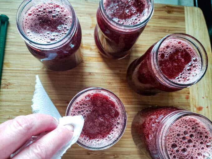 Wiping rims of jars with damp paper towel.