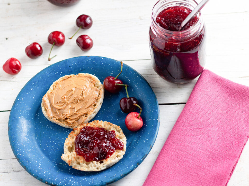 English muffin topped with peanut butter and cherry jam.