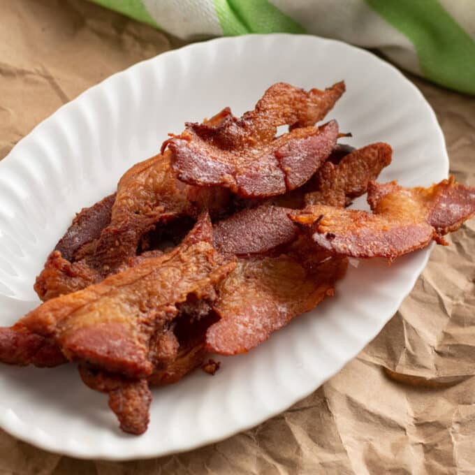 Slices of homemade maple bacon on white plate.