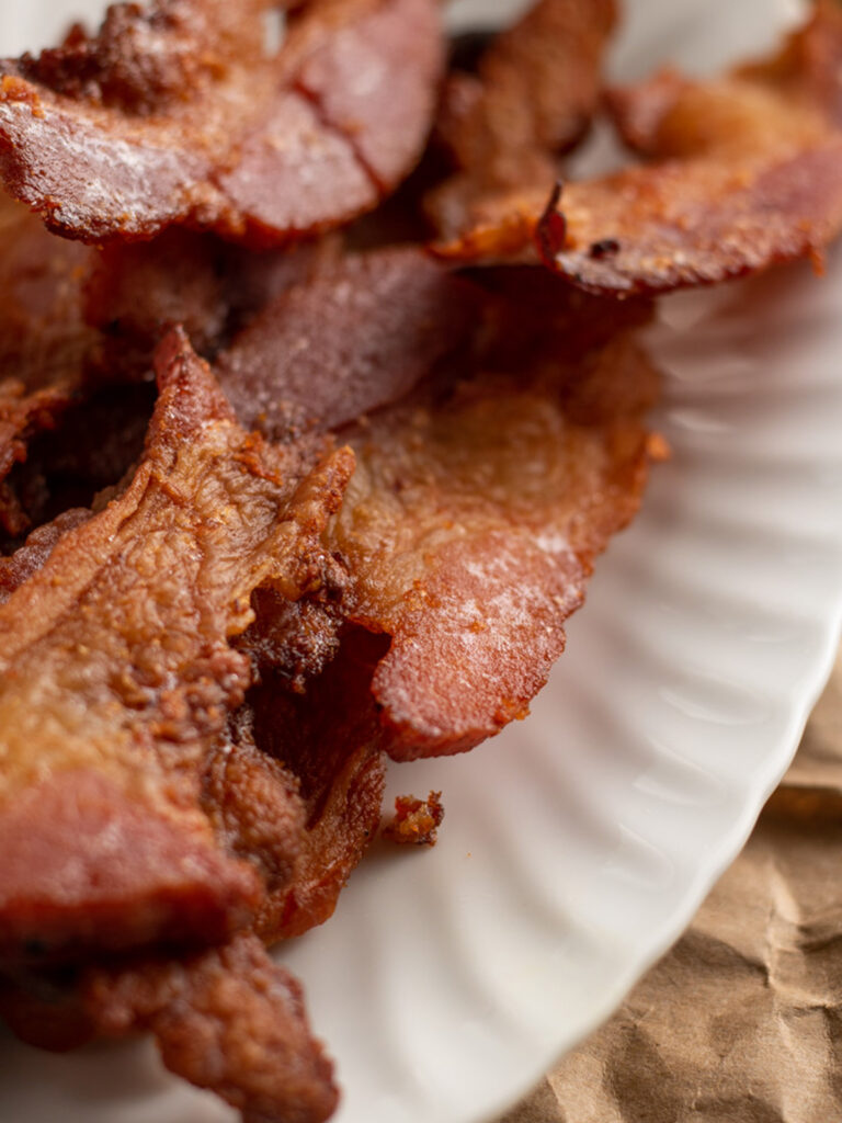 Close up of bacon on white plate.