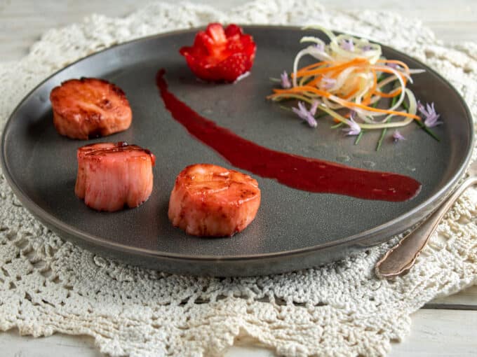 Seared scallops on plate with antiques crocheted doily.
