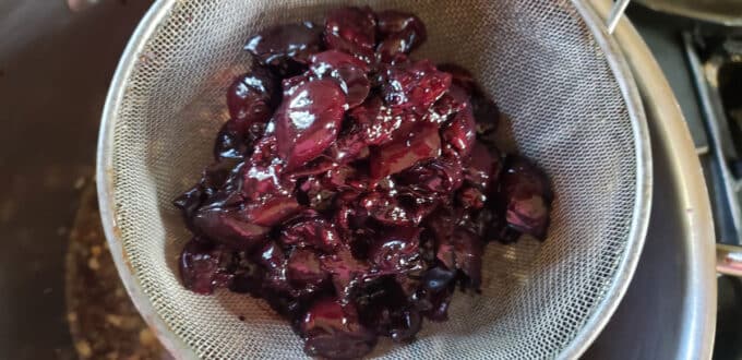 Strainer filled with cherries.