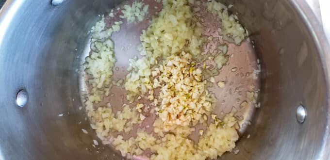 Garlic added to onions in pot.