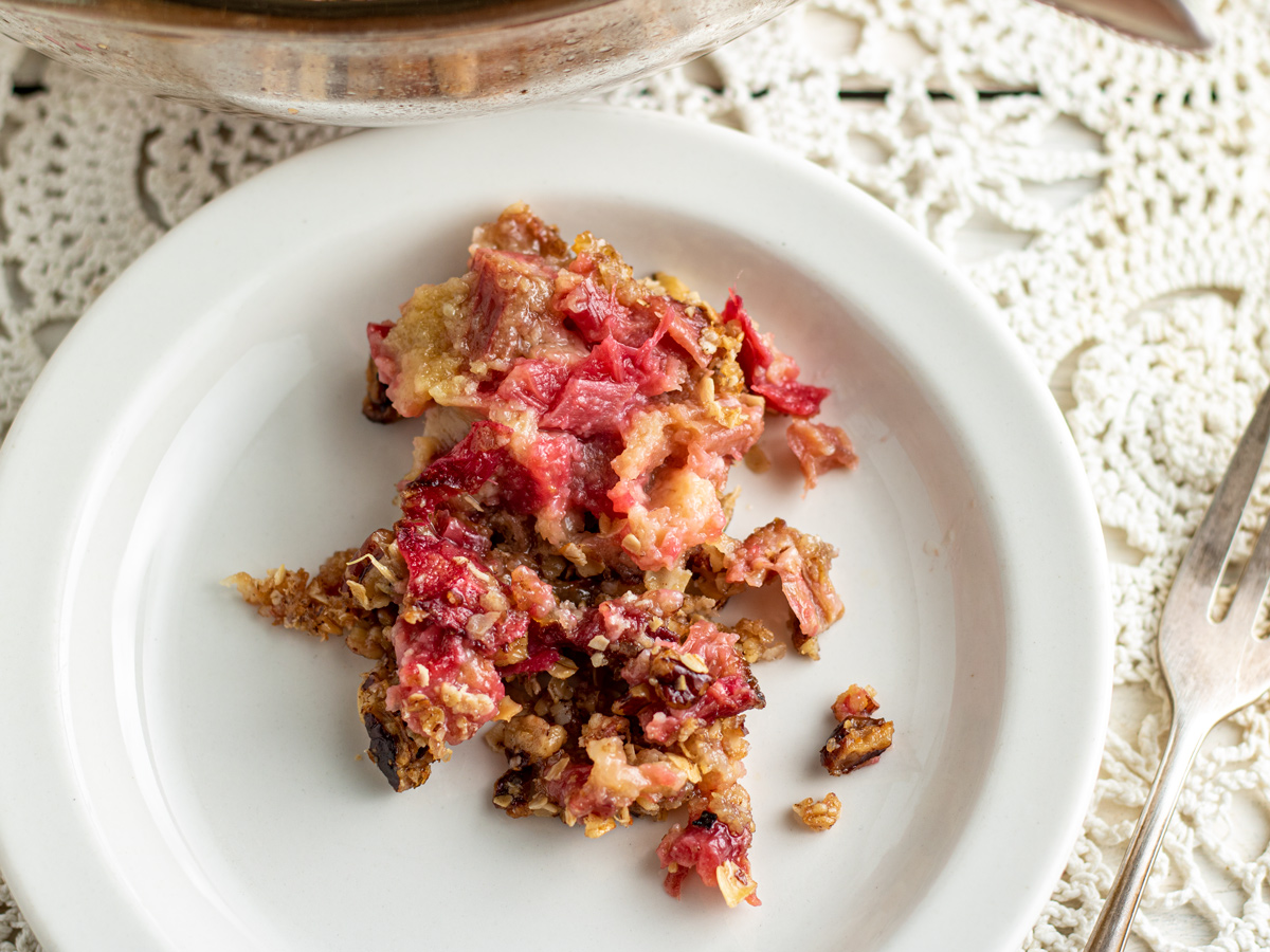 Serving of colorful rhubarb crisp on white plate.