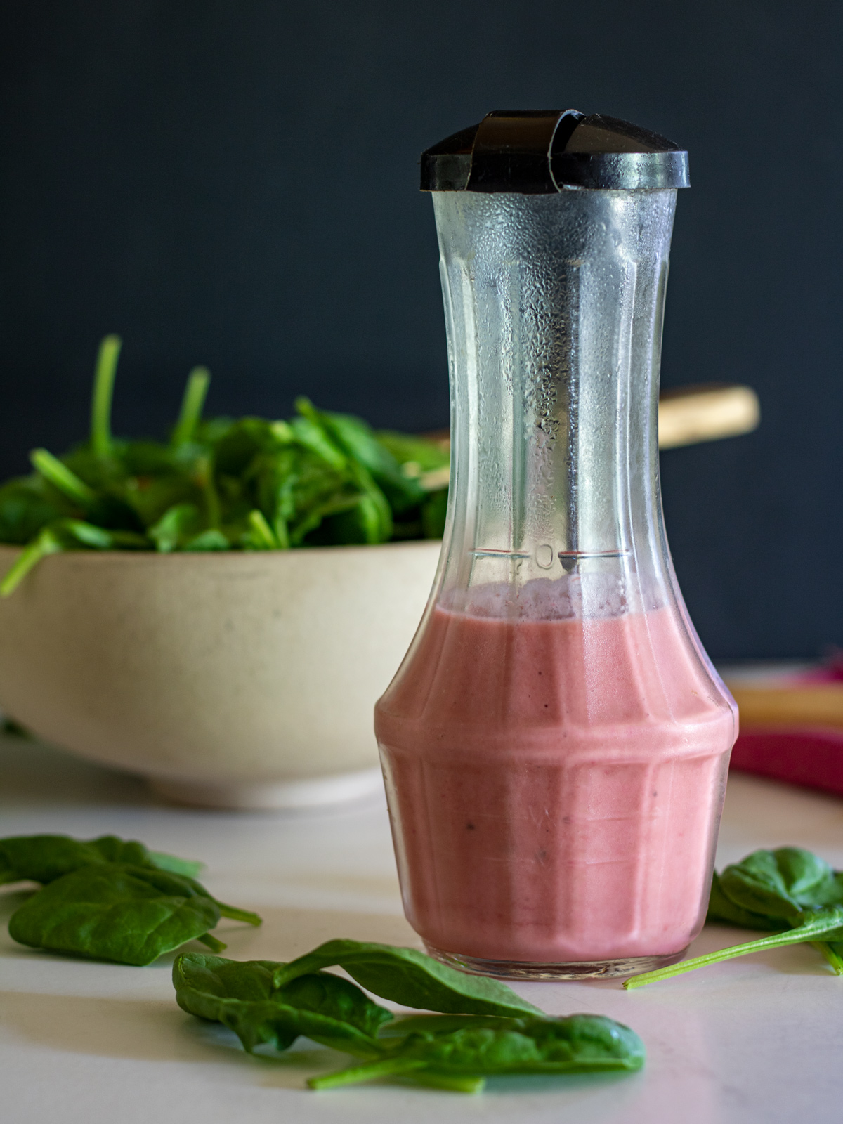 Rhubarb vinaigrette in a cruet with spinach salad in the background.