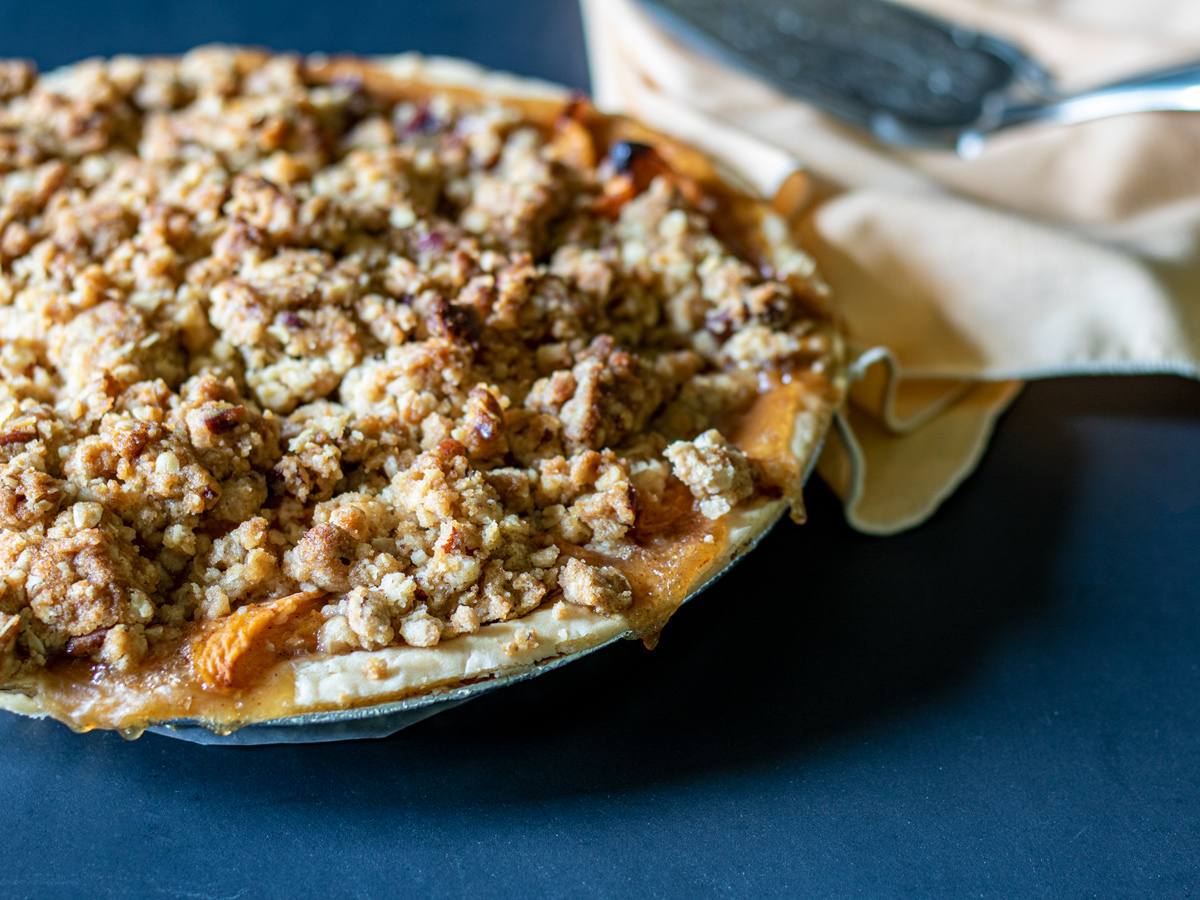 Whole apricot pie on a black background.