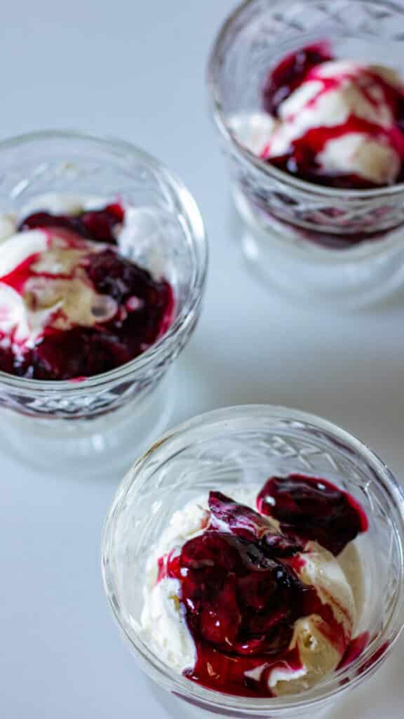 3 bowls of vanilla ice cream topped with cherry pie filling.