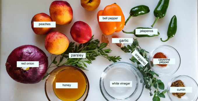Ingredients for peach salsa; red onion, peaches, bell pepper, jalapenos, cayenne pepper, cumin, oregano, garlic, parsley white vinegar, honey.