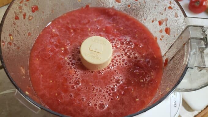 Crushed tomatoes in food processor container.