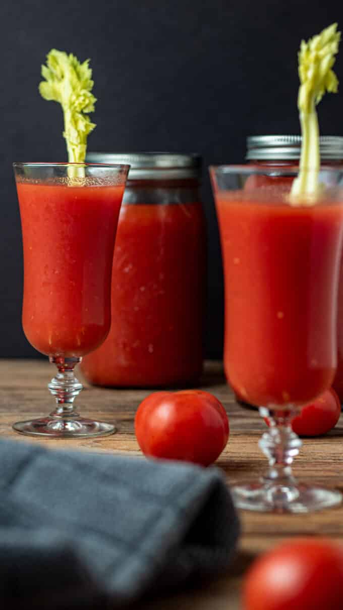 Glasses and jars of tomato juice with fresh tomatoes.