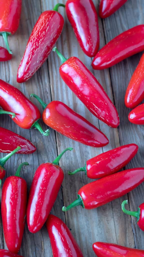 Red jalapenos on barnwood board.