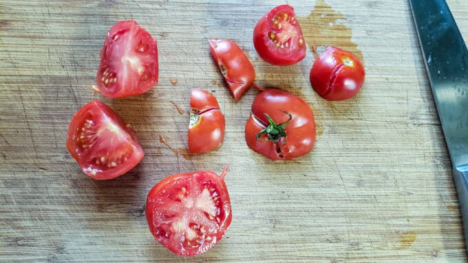 Halved tomatoes on cutting board.