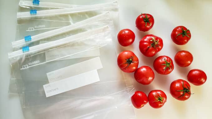 Fresh tomatoes and freezer bags on white board.