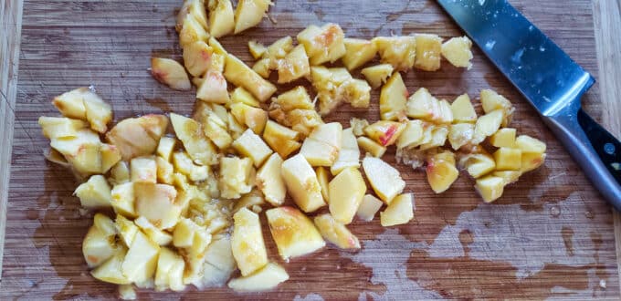 Chopped peeled peaches on cutting board.