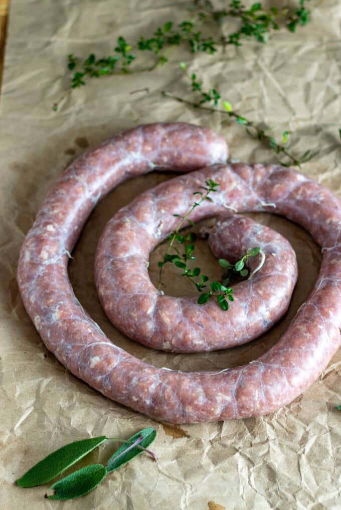 Venison sausage coil with fresh herbs for garnish.