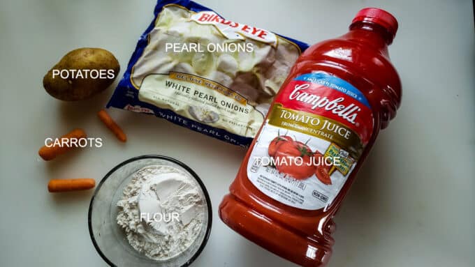 Ingredients for stew; tomato juice, flour, carrots, potatoes, pearl onions.