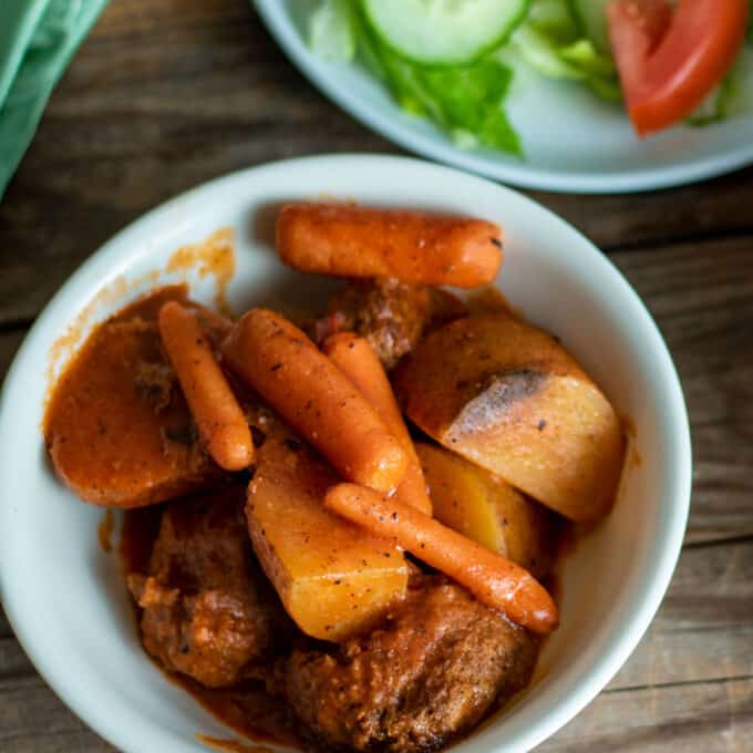 Oven meatball stew in white bowl with side salad.