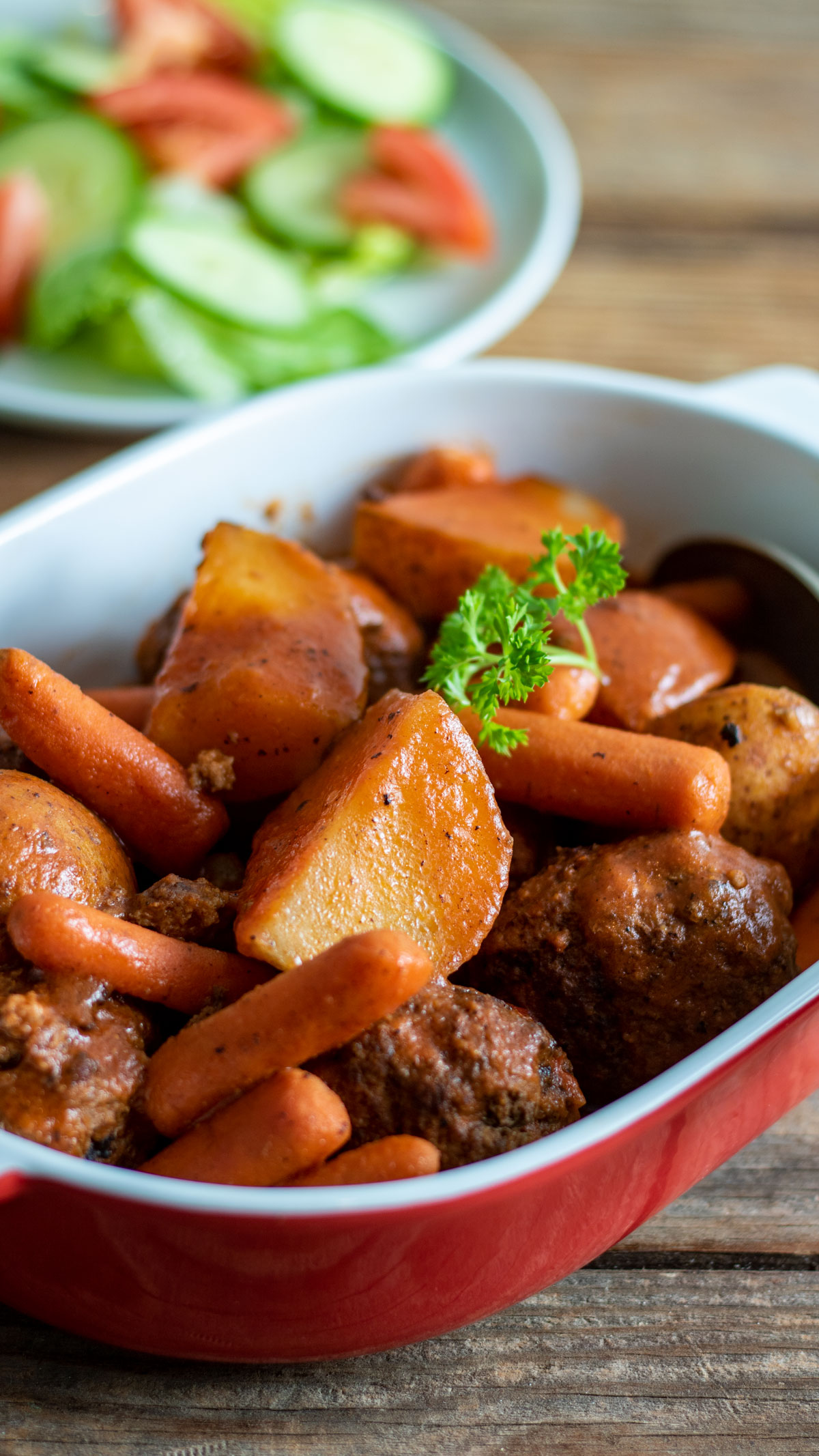 Meatball stew in red casserole dish.