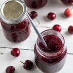 Jar of cherry jam with spoon.