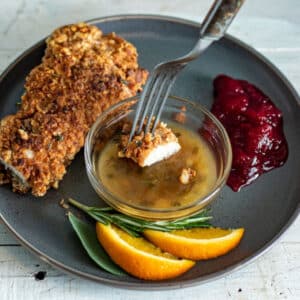 Fork dipping piece of turkey schnitzel in orange sauce.