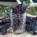 Dried deer jerky standing up in glass jar.