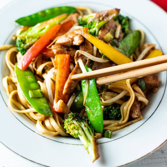 Chopsticks grabbing vegetables from bowl.