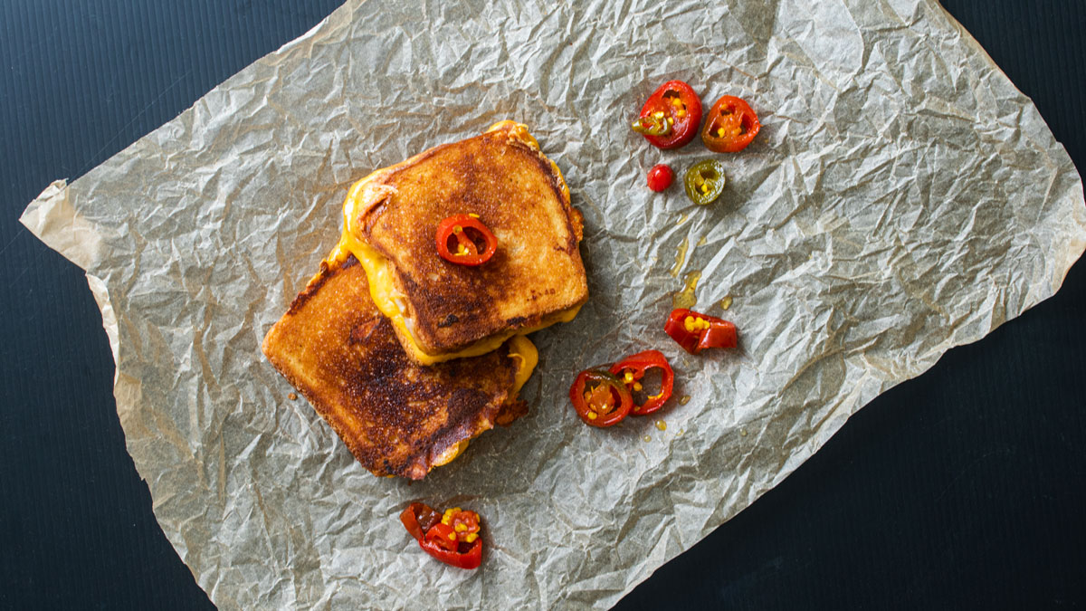 2 sandwiches topped with candied jalapenos.