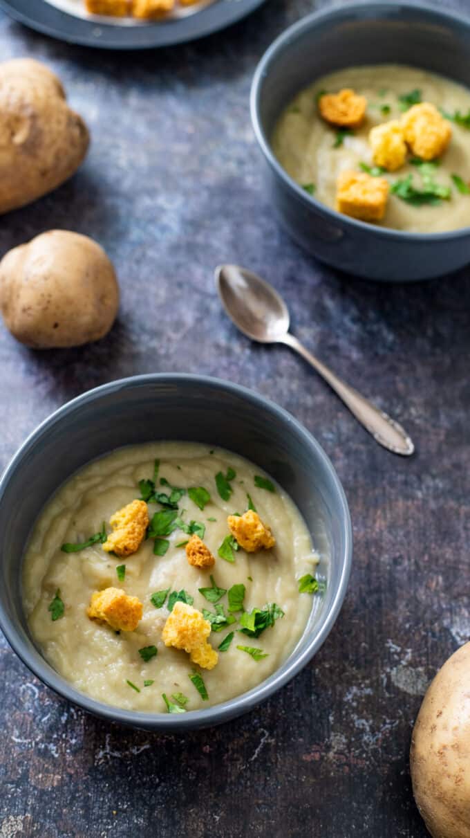 Two bowls of steaming soup on gray background.