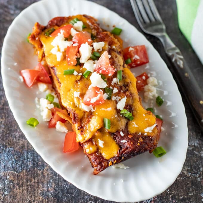 Overhead view of enchiladas on white plate.